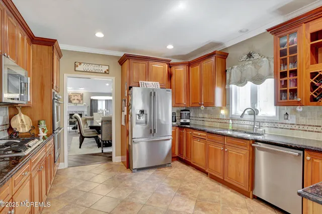 a kitchen with stainless steel appliances granite countertop a stove a sink dishwasher a refrigerator and a oven with wooden cabinets