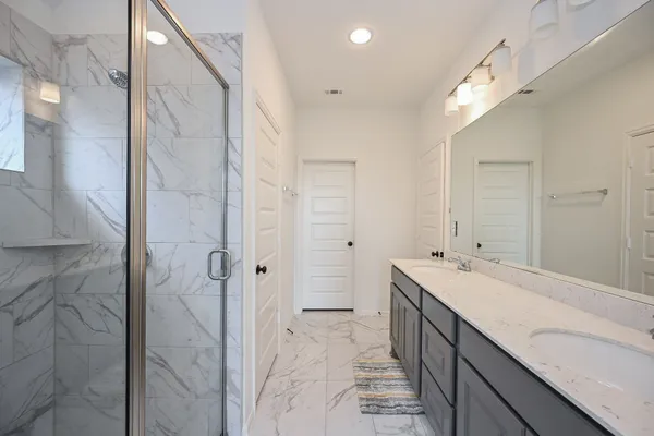a bathroom with a double vanity sink mirror and shower