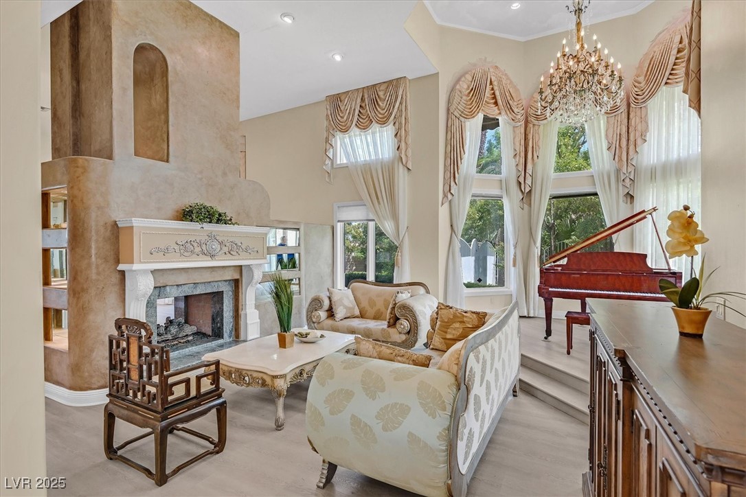 3372 Westwind Road Las Vegas, NV 89146 - Photo 21 of 39 Living area featuring a high end fireplace, a towering ceiling, light wood finished floors, a chandelier, and recessed lighting