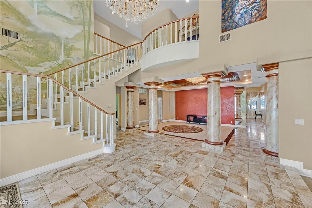 3372 Westwind Road Las Vegas, NV 89146 - Photo 5 of 39 Foyer with decorative columns, stairs, a chandelier, and a towering ceiling