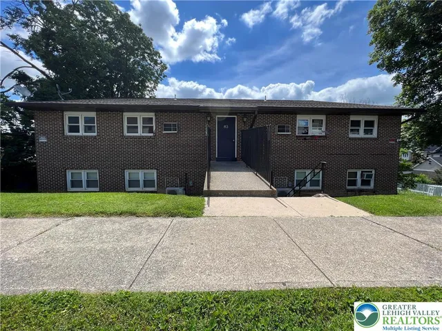 a front view of house with yard and trees in the background