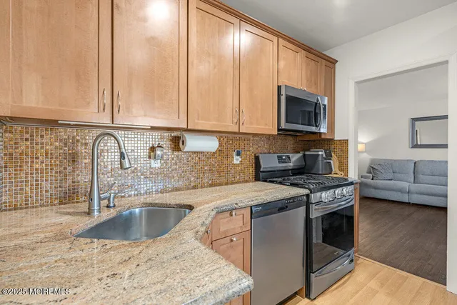 a kitchen with stainless steel appliances granite countertop a refrigerator a stove top oven a sink and dishwasher