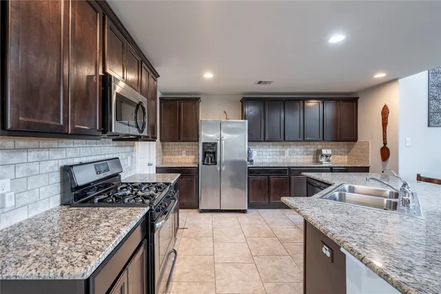 a kitchen with stainless steel appliances granite countertop a sink refrigerator and cabinets