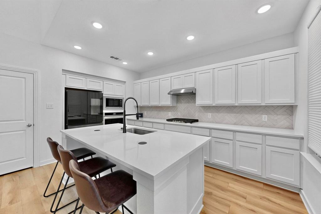2017 Fall Crk Cove Mesquite, TX 75181 - Photo 13 of 40 Kitchen with white cabinets, light wood finished floors, decorative backsplash, black appliances, and recessed lighting