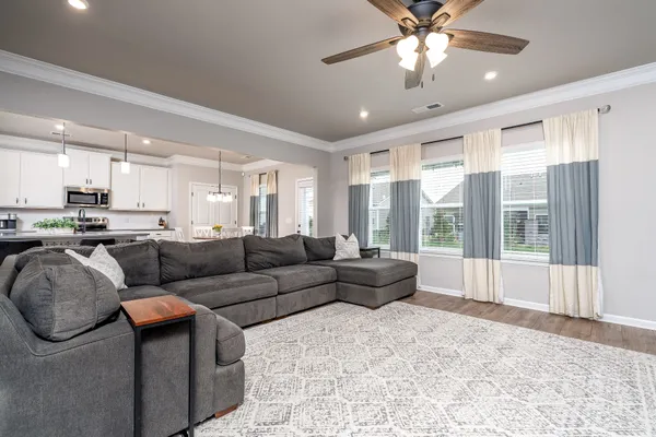 a living room with furniture and a large window with kitchen view