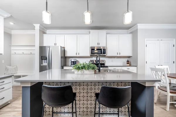 a kitchen with stainless steel appliances granite countertop a stove a refrigerator a sink a dining table and chairs with wooden floor