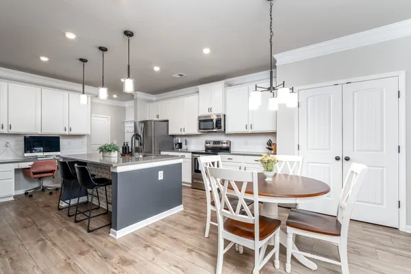 a kitchen with kitchen island granite countertop a dining table chairs and white cabinets