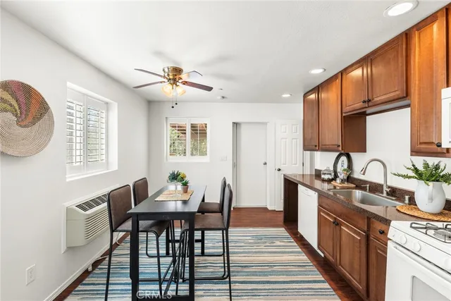 a kitchen with stainless steel appliances granite countertop a stove top oven a sink a dining table and chairs with wooden floor