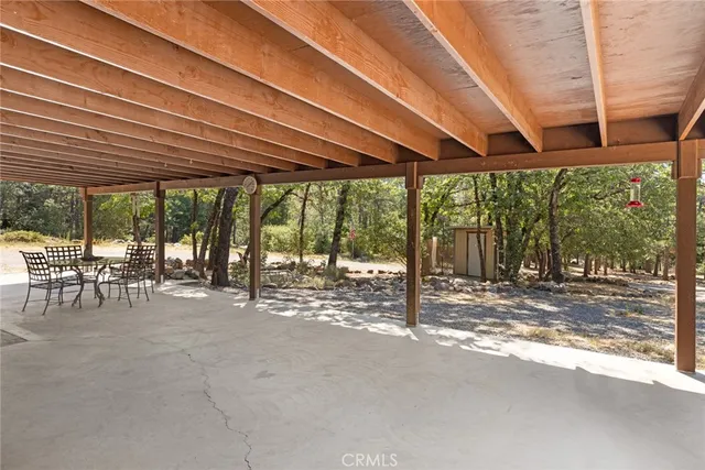 a view of a patio with table and chairs under an umbrella with a big yard