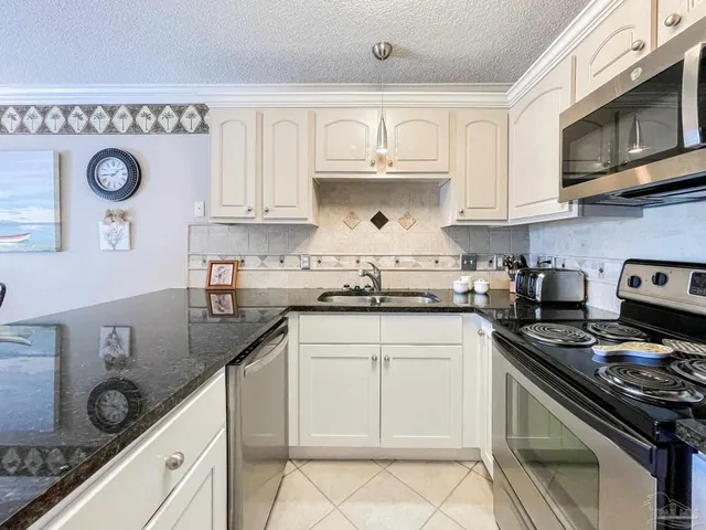 a kitchen with kitchen island granite countertop a sink a stove and cabinets