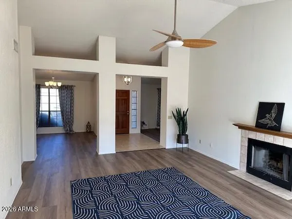 a view of a livingroom with wooden floor a ceiling fan and a fireplace