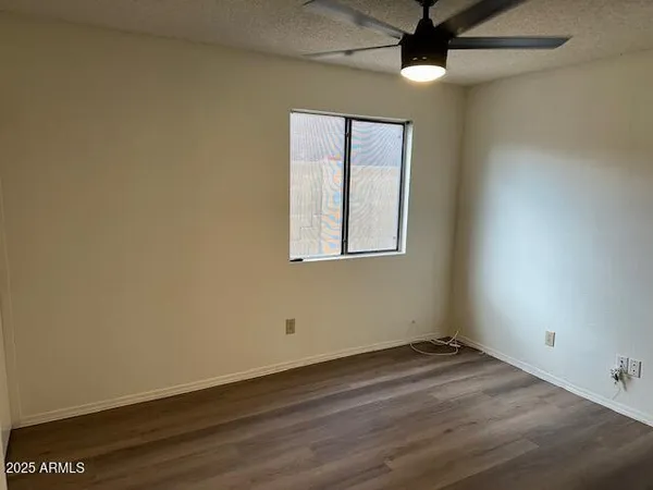 an empty room with wooden floor and ceiling fan