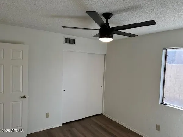 an empty room with wooden floor fan and windows
