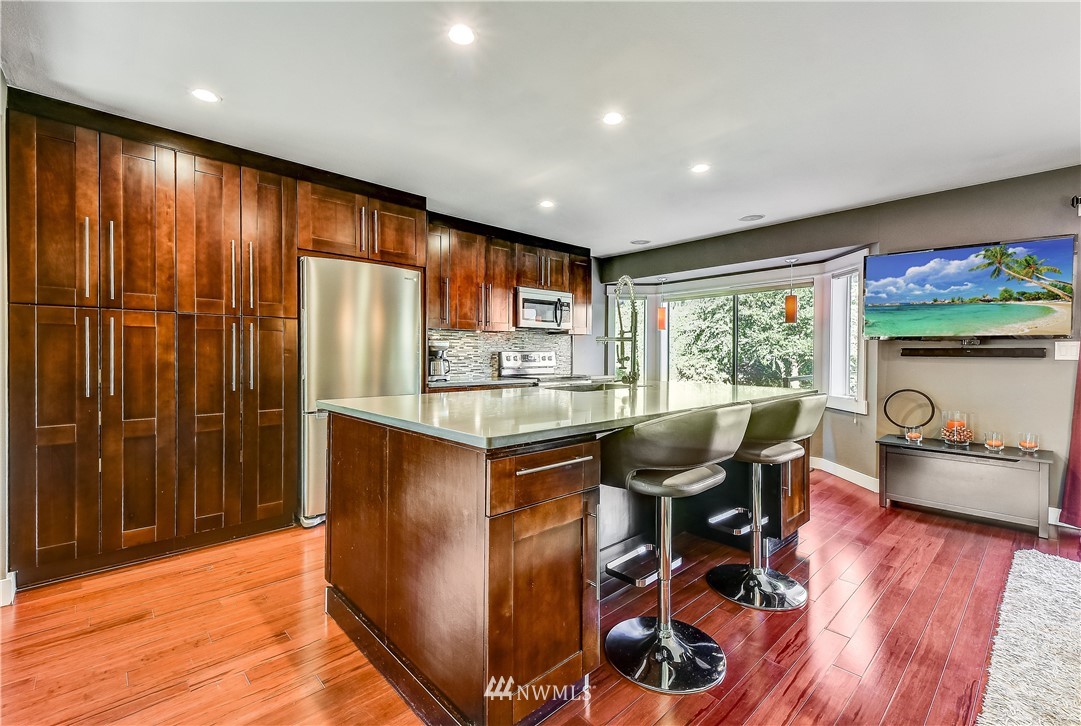 1307 221st Place Southwest Bothell, WA 98021 - Photo 7 of 20 a open kitchen with stainless steel appliances granite countertop a stove top oven a dining table and chairs with wooden floor