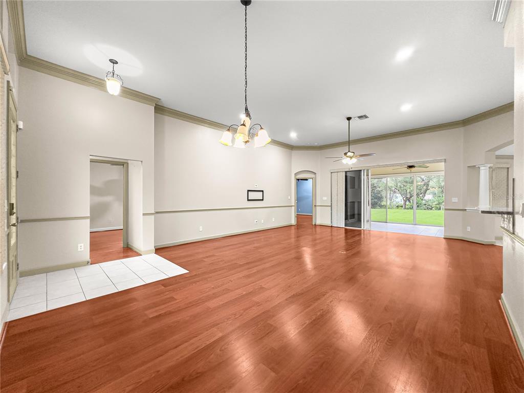 8045 Waterbury Way Mount Dora, FL 32757 - Photo 17 of 56 a view of an empty room with wooden floor kitchen view and a window