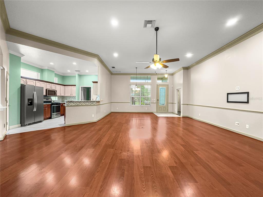 8045 Waterbury Way Mount Dora, FL 32757 - Photo 18 of 56 a view of an empty room with wooden floor and a kitchen