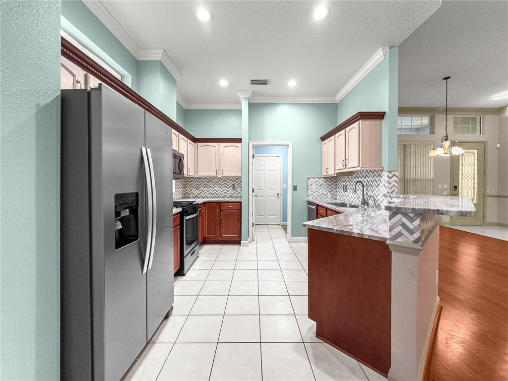 8045 Waterbury Way Mount Dora, FL 32757 - Photo 8 of 56 a kitchen with stainless steel appliances granite countertop a refrigerator and a sink