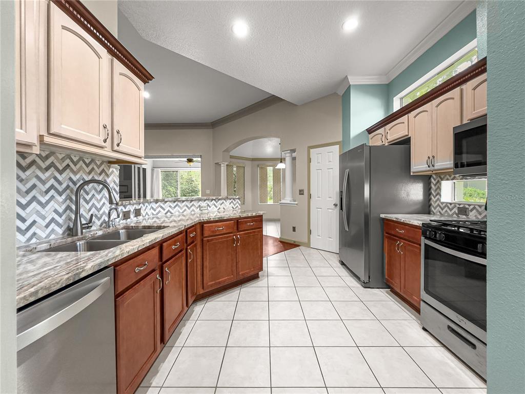 8045 Waterbury Way Mount Dora, FL 32757 - Photo 10 of 56 a large kitchen with stainless steel appliances granite countertop a stove and a sink