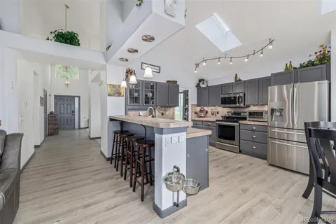 a kitchen with stainless steel appliances kitchen island granite countertop a table chairs and a refrigerator