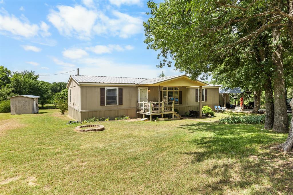 439 Slayden Road Sunset, TX 76270 - Photo 2 of 27 Single-story residence featuring a metal roof, an elevated front porch with wood railings, a bay window, and a light-colored exterior finish