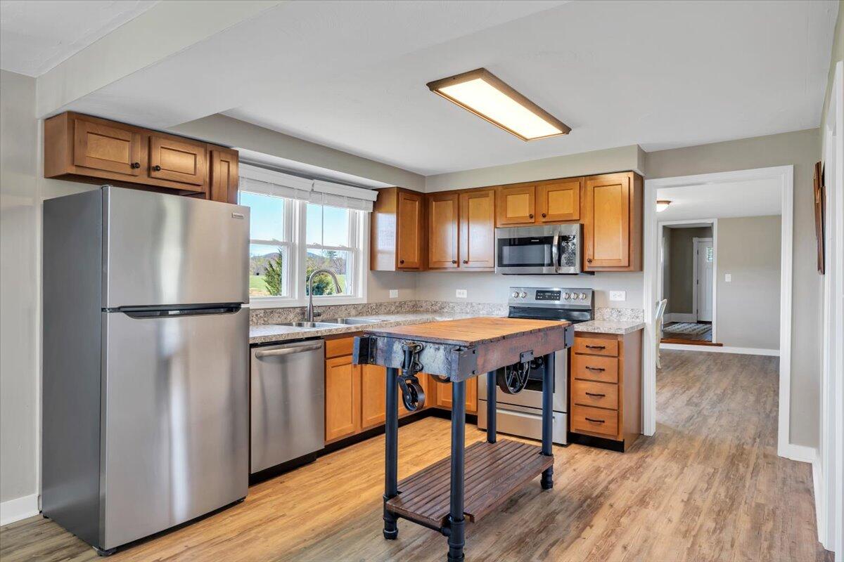 3861 Wheatland Road Bedford, VA 24523 - Photo 24 of 99 a kitchen with stainless steel appliances granite countertop a refrigerator a sink dishwasher a stove and a dining table with wooden floor