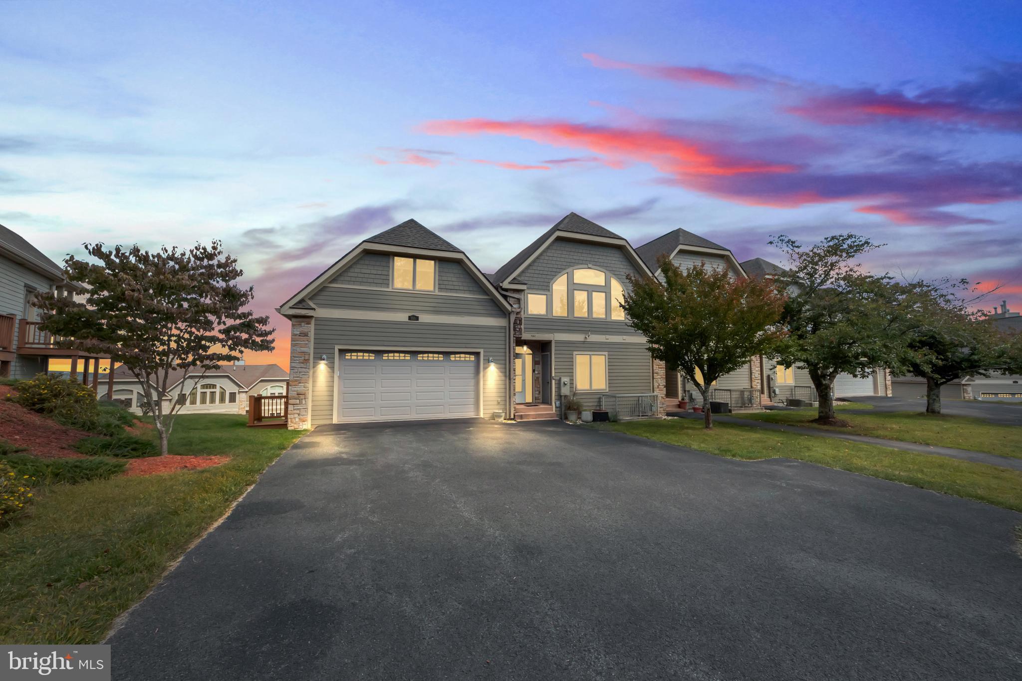 a front view of a house with a garden and trees