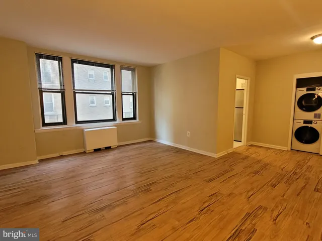 a view of an empty room with a window and wooden floor
