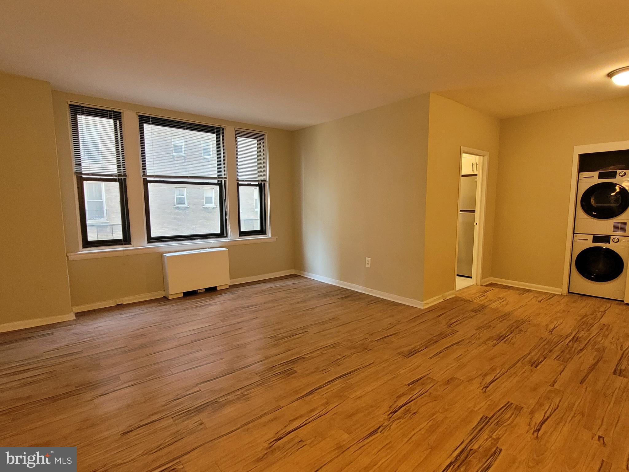 a view of an empty room with a window and wooden floor