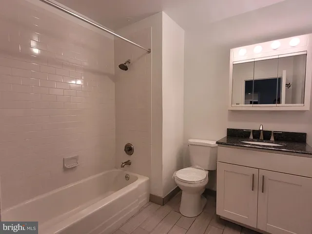 a bathroom with a granite countertop toilet a sink and a bathtub