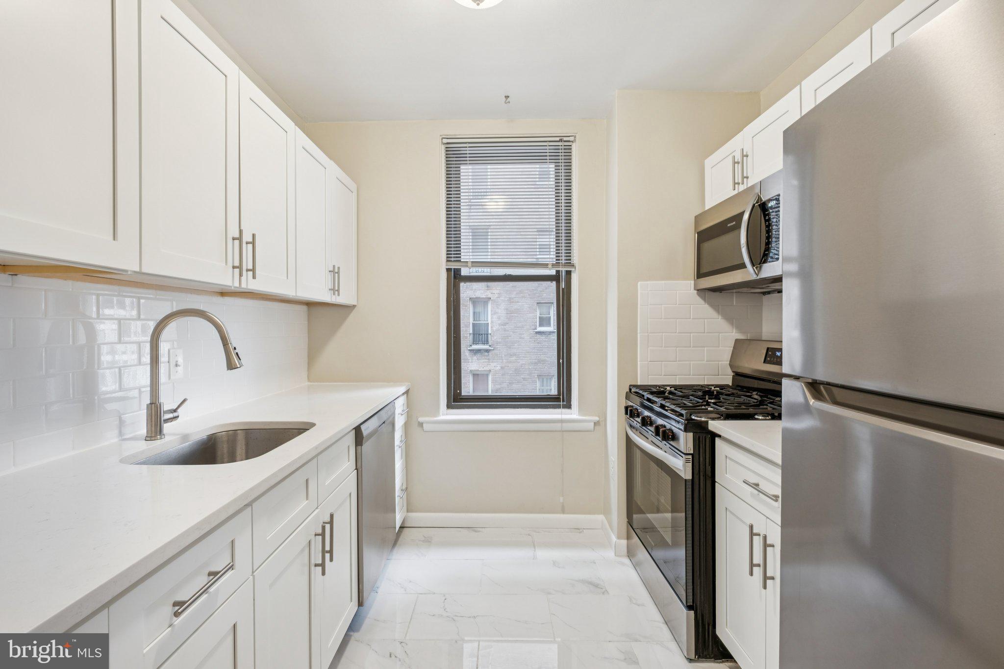 135 South 19th Street, Unit 908 Philadelphia, PA 19103 - Photo 5 of 18 a kitchen with granite countertop a sink stove and refrigerator