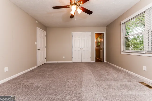 a view of an empty room with window and chandelier fan