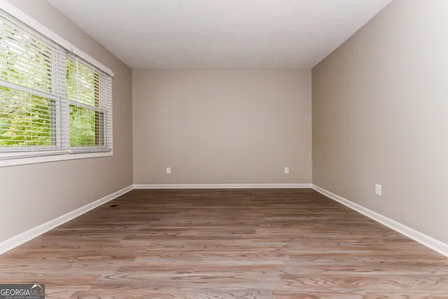 a view of an empty room with wooden floor and a window