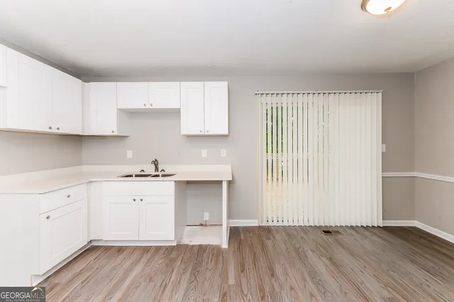 a kitchen with wooden floors and white cabinets