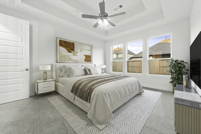a bedroom with a large bed and a chandelier fan