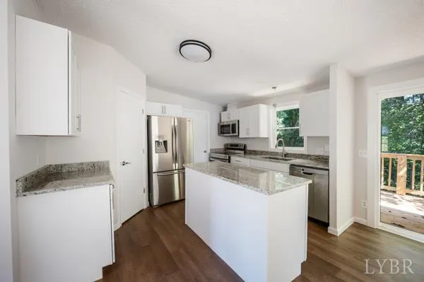 a kitchen with a refrigerator a stove top oven a sink dishwasher and white cabinets next to a window