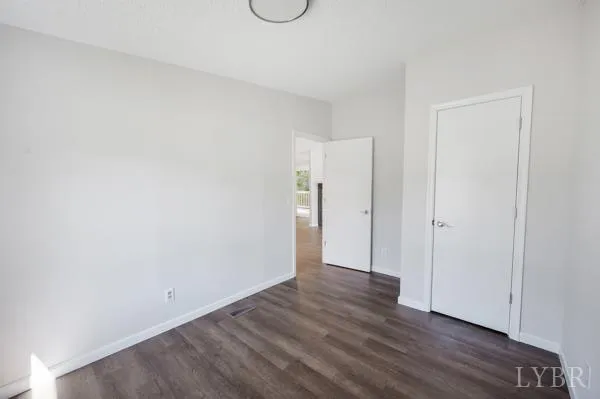 a view of an empty room with wooden floor and closet