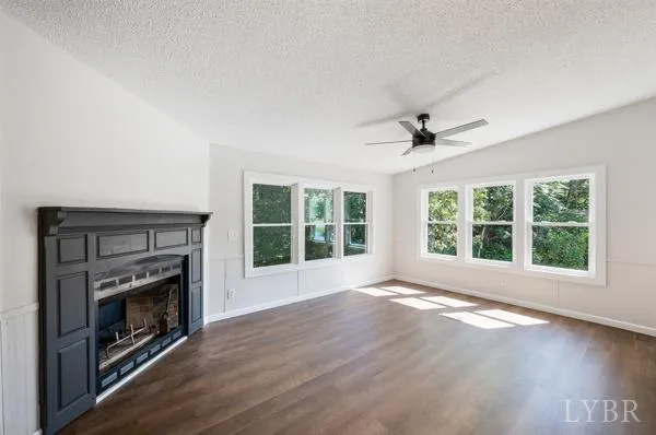 a view of an empty room with wooden floor fireplace and a window