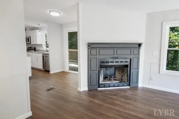 a view of kitchen and empty room with a fireplace
