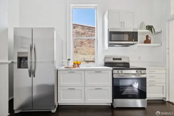a kitchen with stainless steel appliances a refrigerator a stove and wooden floor