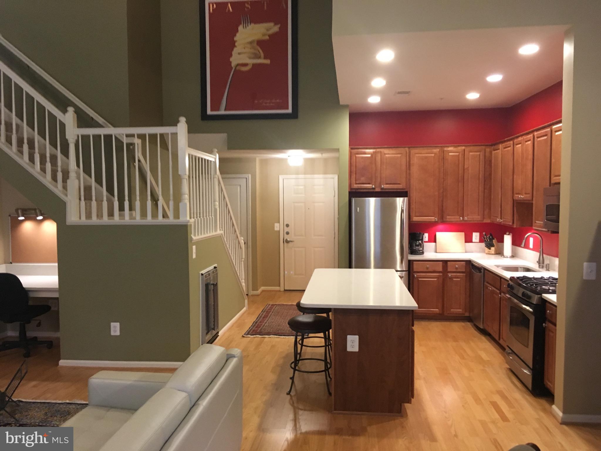 12000 Market Street, Unit 430 Reston, VA 20190 - Photo 3 of 24 a kitchen with stainless steel appliances kitchen island granite countertop a refrigerator a stove and a sink