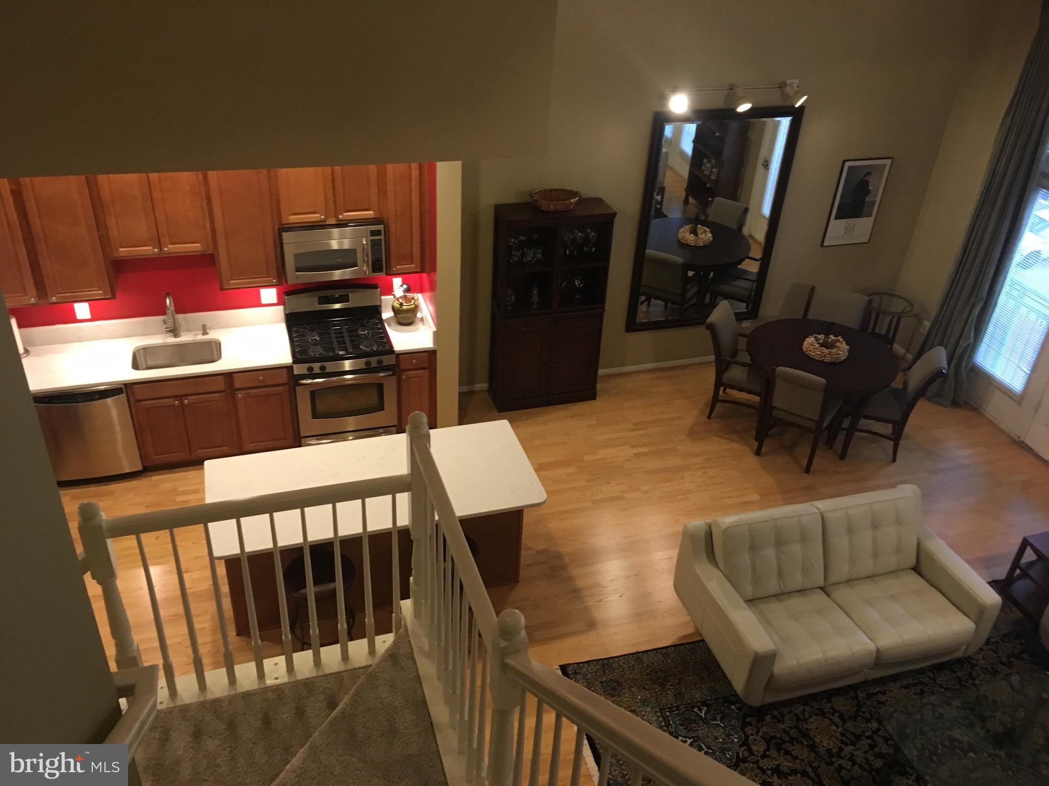 12000 Market Street, Unit 430 Reston, VA 20190 - Photo 5 of 24 a living room with furniture a flat screen tv and kitchen view