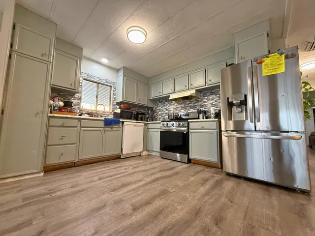 a kitchen with stainless steel appliances granite countertop a sink and a refrigerator