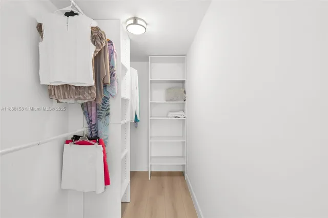 a view of walk in closet with clothes and white walls