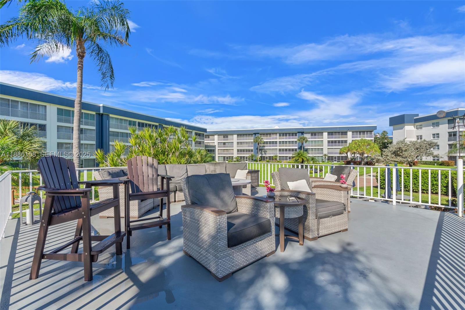 3301 Spanish Trail, Unit 207 Delray Beach, FL 33483 - Photo 27 of 38 a view of a patio with couches table and chairs potted plants and palm tree