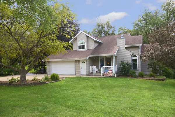 a front view of a house with a garden and trees