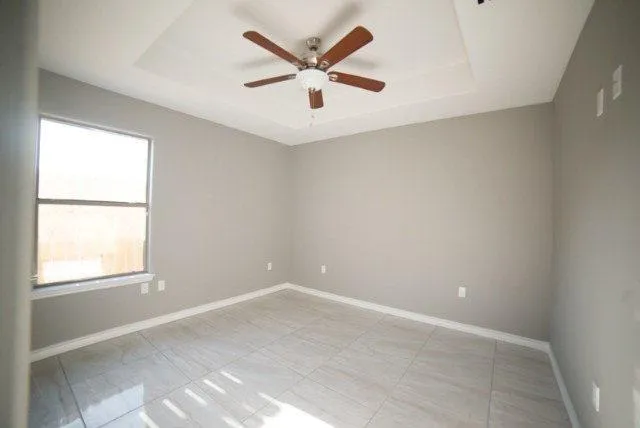 an empty room with ceiling fan and window