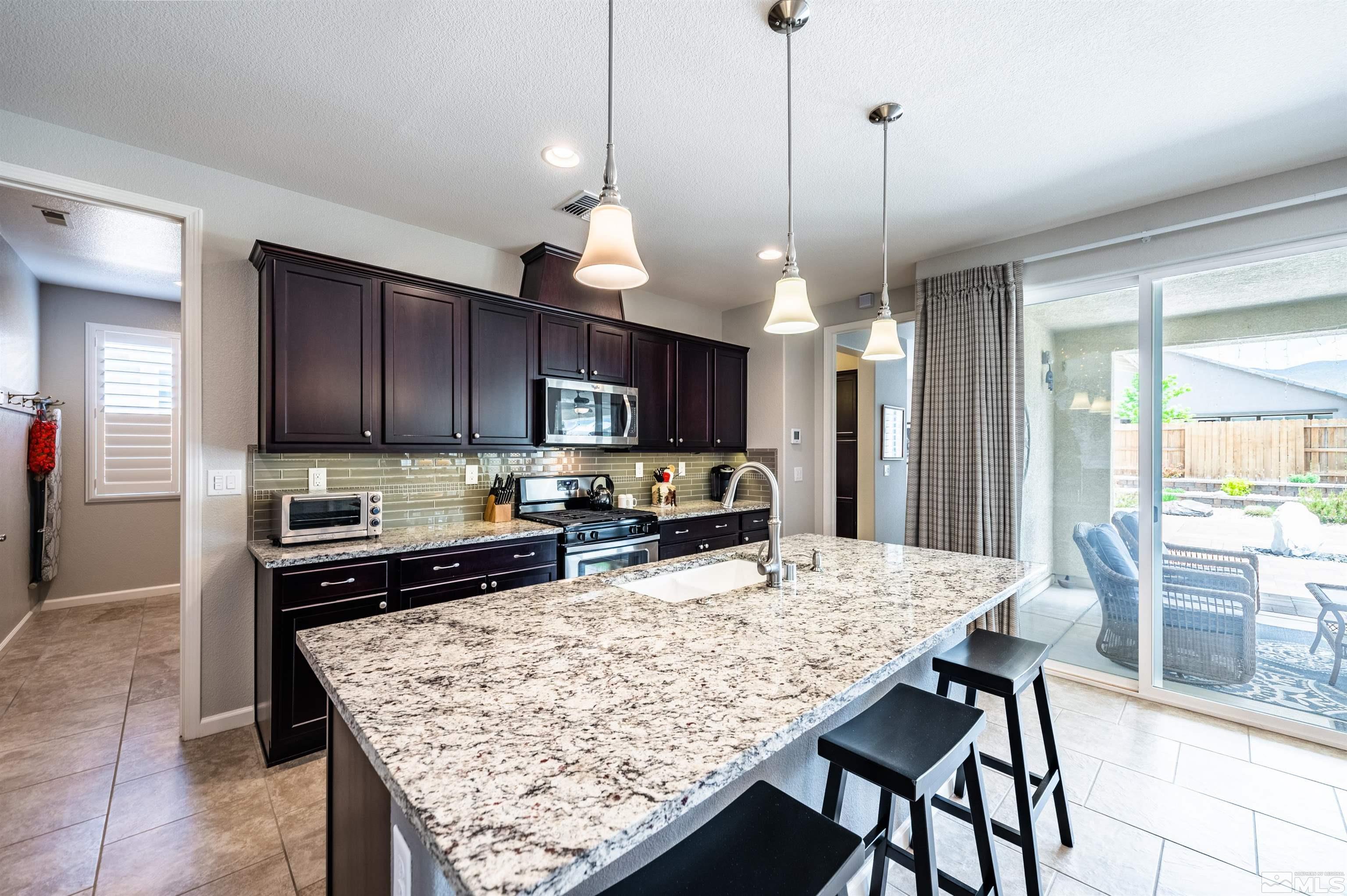 9860 Nahar Lane Reno, NV 89521 - Photo 12 of 40 a kitchen with stainless steel appliances granite countertop table chairs sink refrigerator and stove