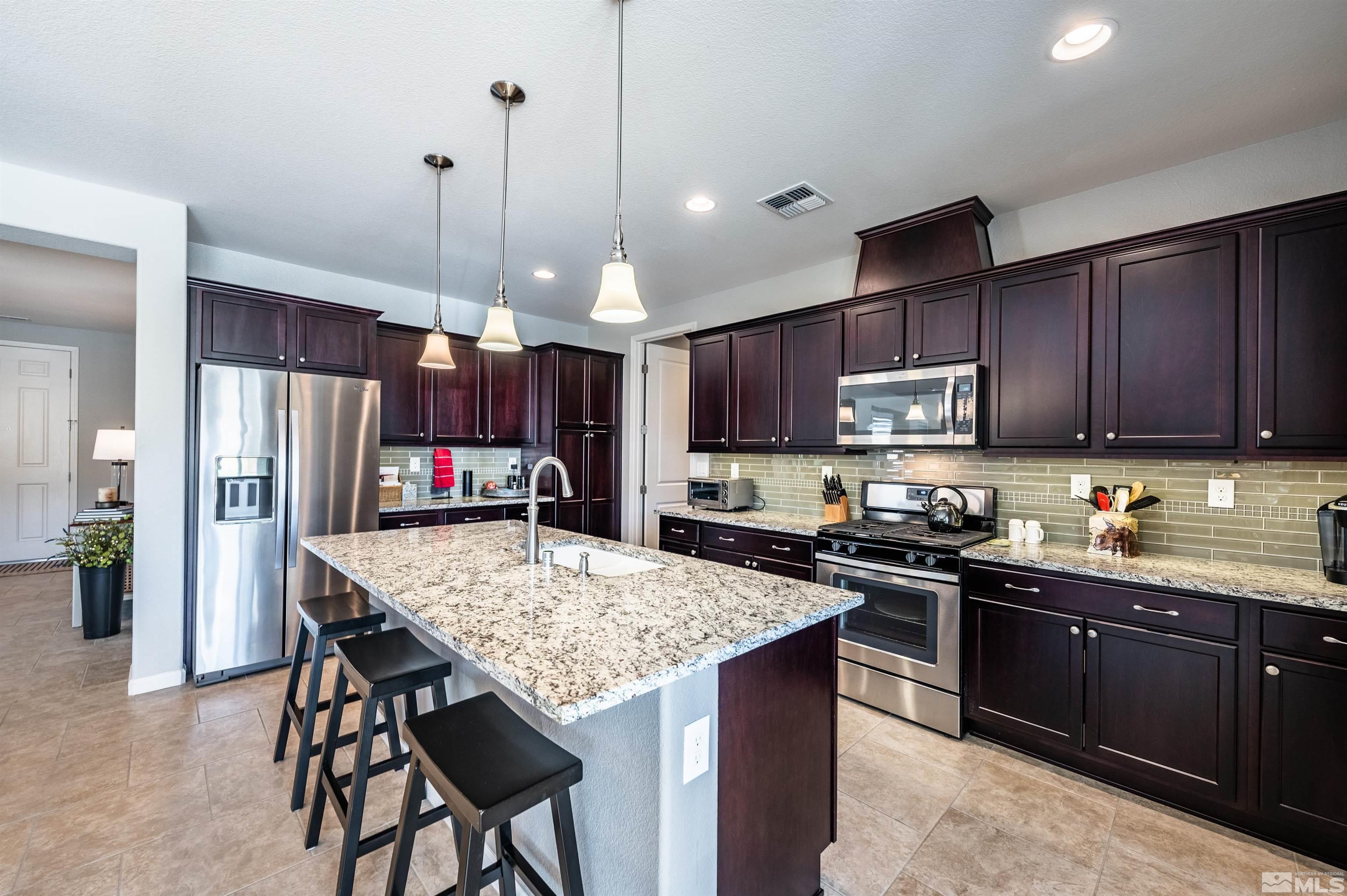 9860 Nahar Lane Reno, NV 89521 - Photo 13 of 40 a kitchen with kitchen island granite countertop wooden cabinets a stove a sink and a refrigerator