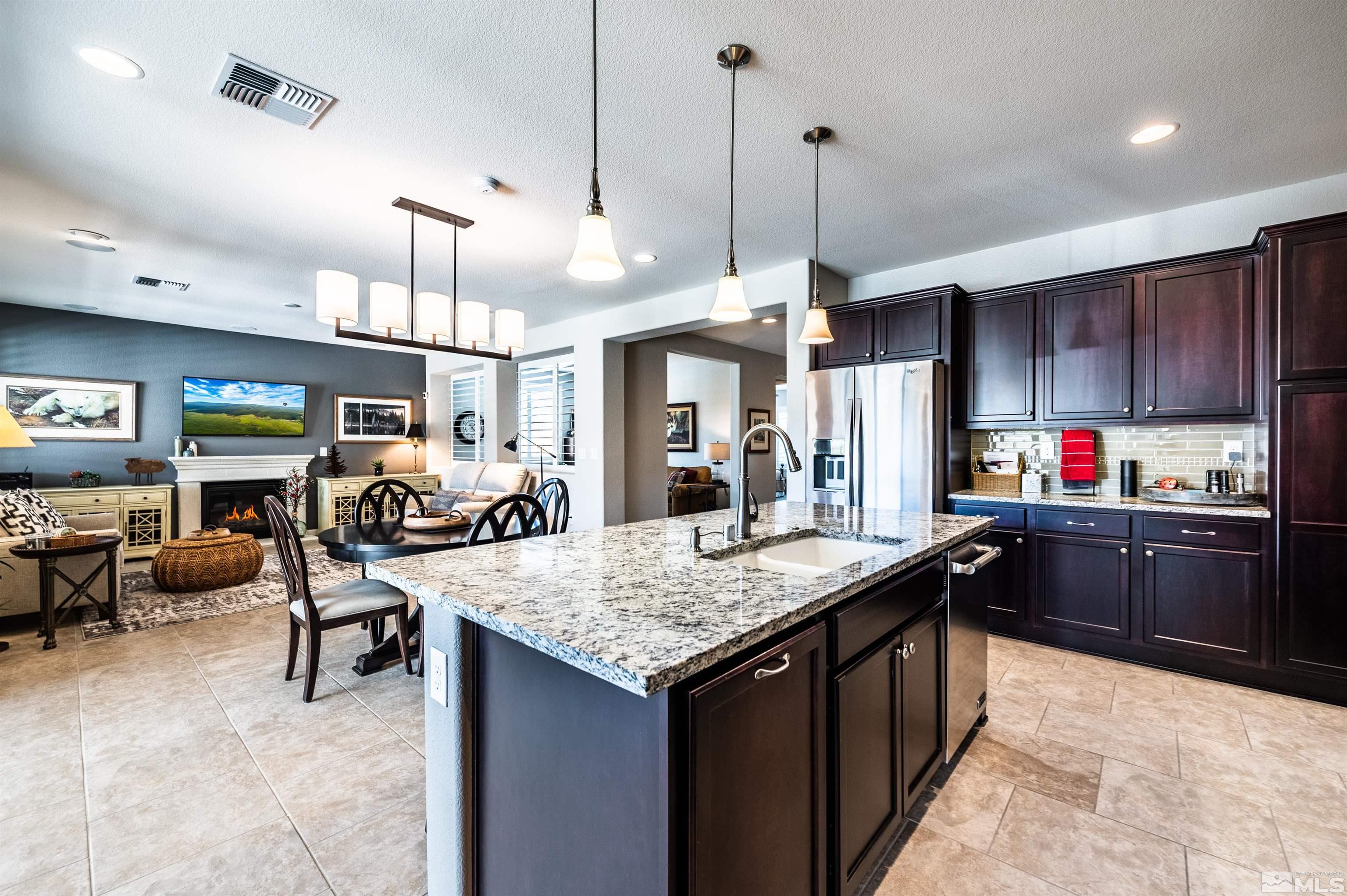 9860 Nahar Lane Reno, NV 89521 - Photo 14 of 40 a kitchen with granite countertop a sink a center island and living room view