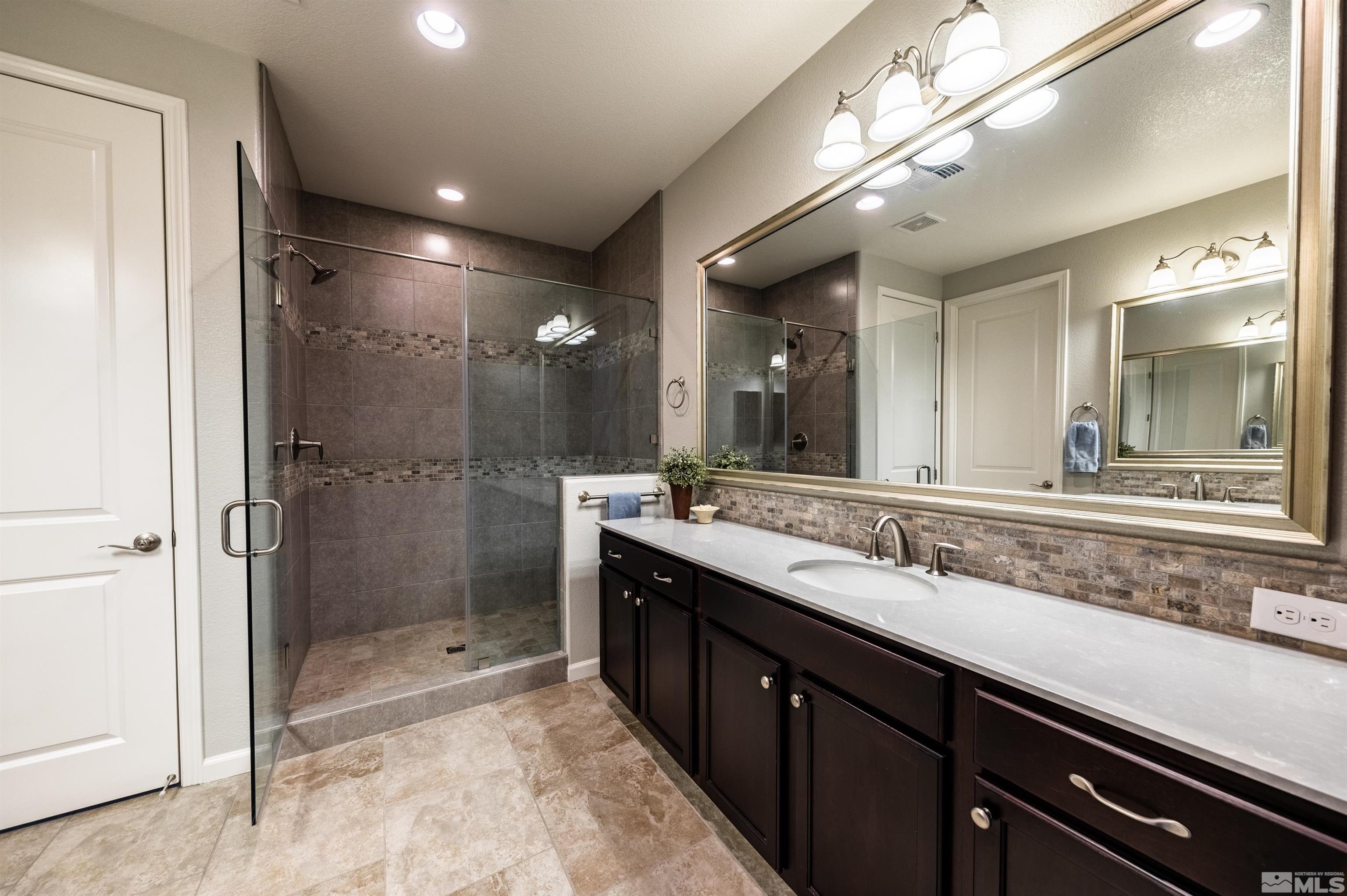 9860 Nahar Lane Reno, NV 89521 - Photo 18 of 40 a bathroom with a shower sink double vanity and a mirror